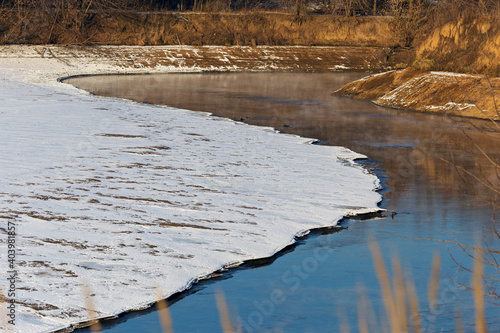 Landscape of a cold autumn river with snow outside the city.