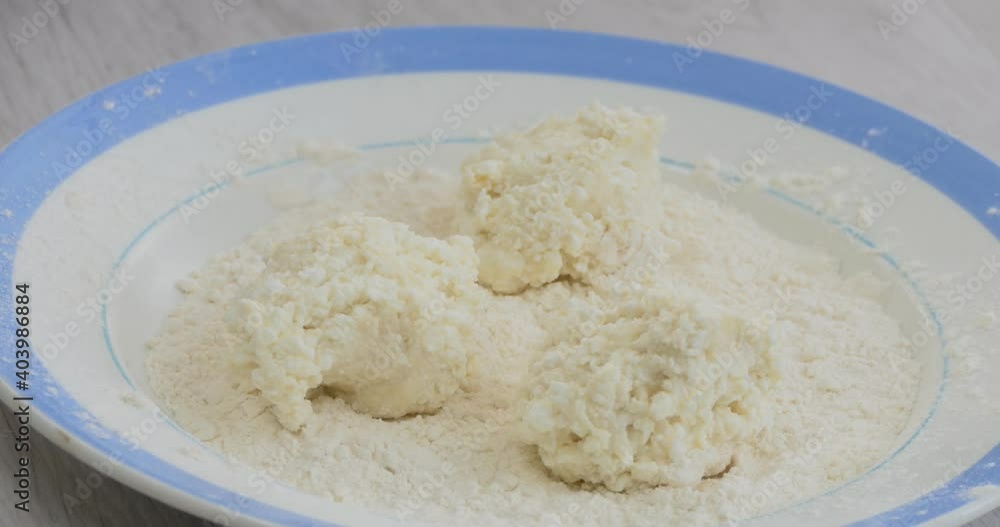 Simple food, Asian cuisine. A woman's hand puts a spoon on a plate with flour balls of cottage cheese for making curd fritters (cheese pancakes). Simple food, Asian cuisine. A woman's hand puts a spoon on a plate with flour balls of cottage cheese for making curd fritters (cheese pancakes).