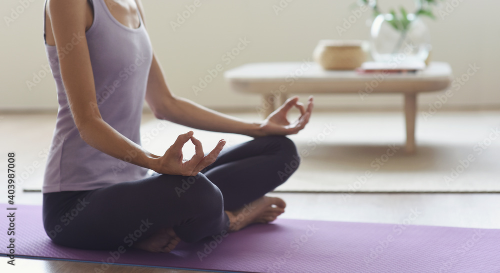 Closeup of young woman meditating and practicing yoga at home. Recreation, self care, yoga training, fitness, breathing exercises, meditation, relaxation, healthy lifestyle concept