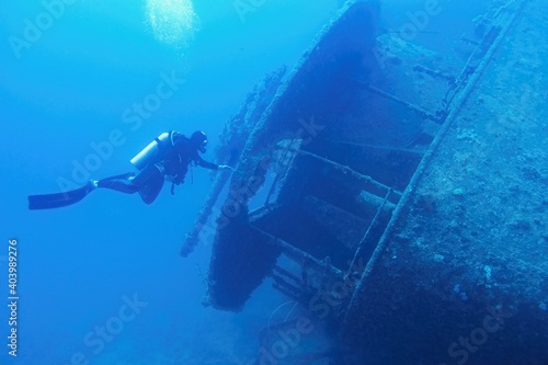 Man scuba diver swimming near the ship wreck in blue deep water. Ship wreck SS Thistlegormm, Red sea Egypt.