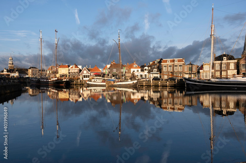 Large sail boats and pleasure yachts mirrored in blue water with sunset in the port of Lemmer in Friesland  Netherlands