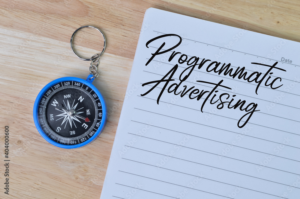 Top view of magnetic compass and notebookwritten with text PROGRAMMATIC ADVERTISING. Business concept. Top view of magnetic compass and notebookwritten with text PROGRAMMATIC ADVERTISING. Business concept.