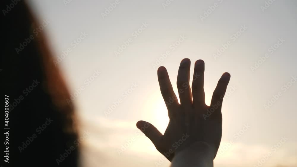 Hand of happy girl at sunset. Sunset between the hands of girl. Happy girl with long hair dreamily stretches out her hand to the sun. Child's dream hand to the sun. happy family concept Hand of happy girl at sunset. Sunset between the hands of girl. Happy girl with long hair dreamily stretches out her hand to the sun. Child's dream hand to the sun. happy family concept