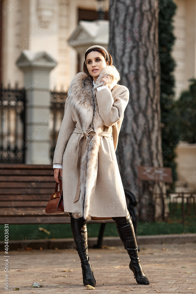 Beautiful girl in fur coat walking in the city. street style