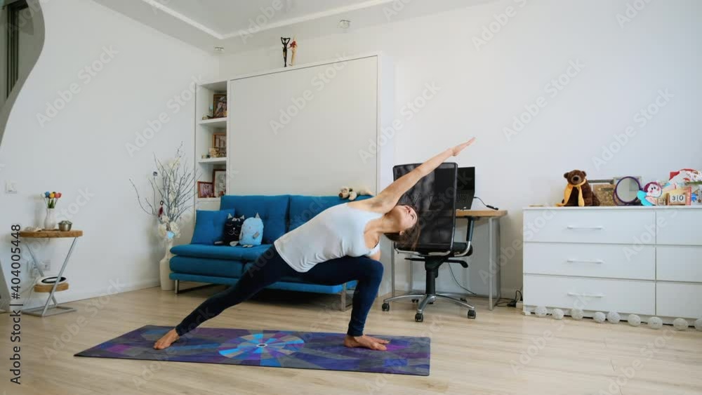 Young woman practicing yoga at home, stretching arm and leg Young woman practicing yoga at home, stretching arm and leg