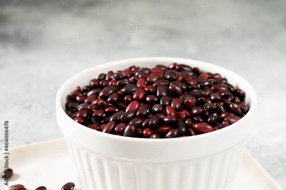 Red beans. Raw red beans in a ceramic bowl on a light gray kitchen table. Organic Natural Vegetarian product Red beans. Raw red beans in a ceramic bowl on a light gray kitchen table. Organic Natural Vegetarian product