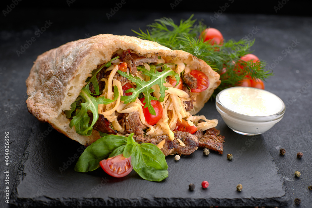 Ταπετσαρία Pita with meat and vegetables, on slate, on a black background