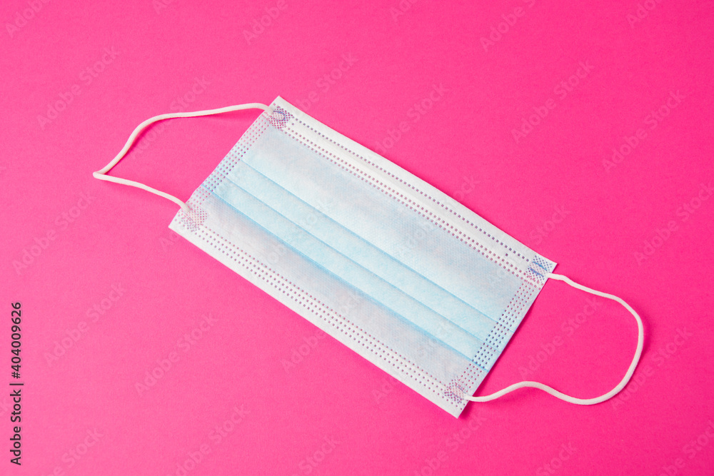 Medical mask on a bright pink background. The concept of extending quarantine and protecting against the virus Medical mask on a bright pink background. The concept of extending quarantine and protecting against the virus