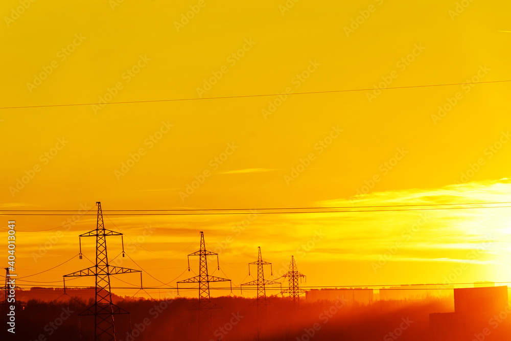 Power lines against the background of an orange sunset. Infrastructure of the city in beautiful sunshine. Copy space