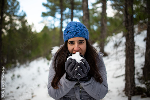pretty brunette woman enjoying the snow on the snowy mountain with blue hat and winter coat