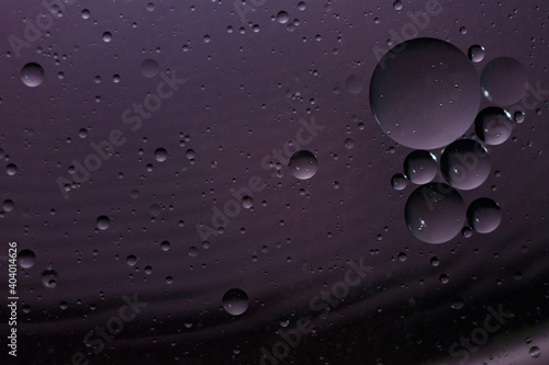 Oil drops in water taken close up on a dark purple background