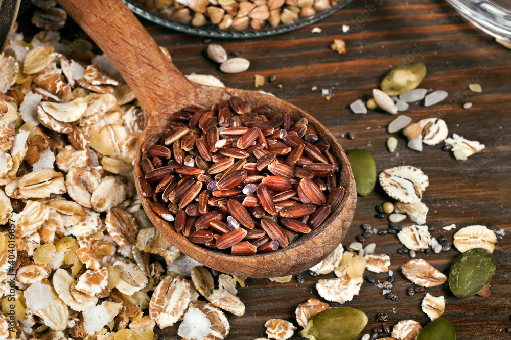 Oat flakes with brown rice, glass jar of green buckwheat, chia and pumpkin seeds on a wooden background. Oat flakes with brown rice, glass jar of green buckwheat, chia and pumpkin seeds on a wooden background.
