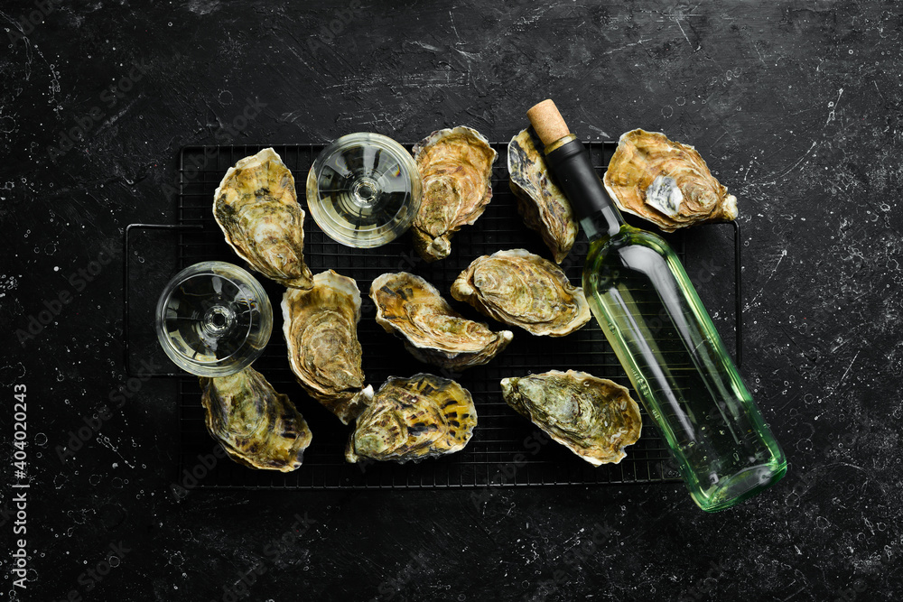 Closed fresh oysters and white wine in glasses on a stone background. Free space for your text. Seafood. Flat lay. Closed fresh oysters and white wine in glasses on a stone background. Free space for your text. Seafood. Flat lay.