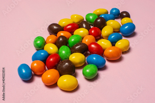 Photography Colorful chocolate dragee on pink background