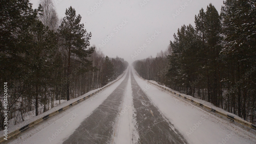The car is driving on a winter road. The car drives on a winter road in a blizzard, top view. Driving a car over rough snowy terrain