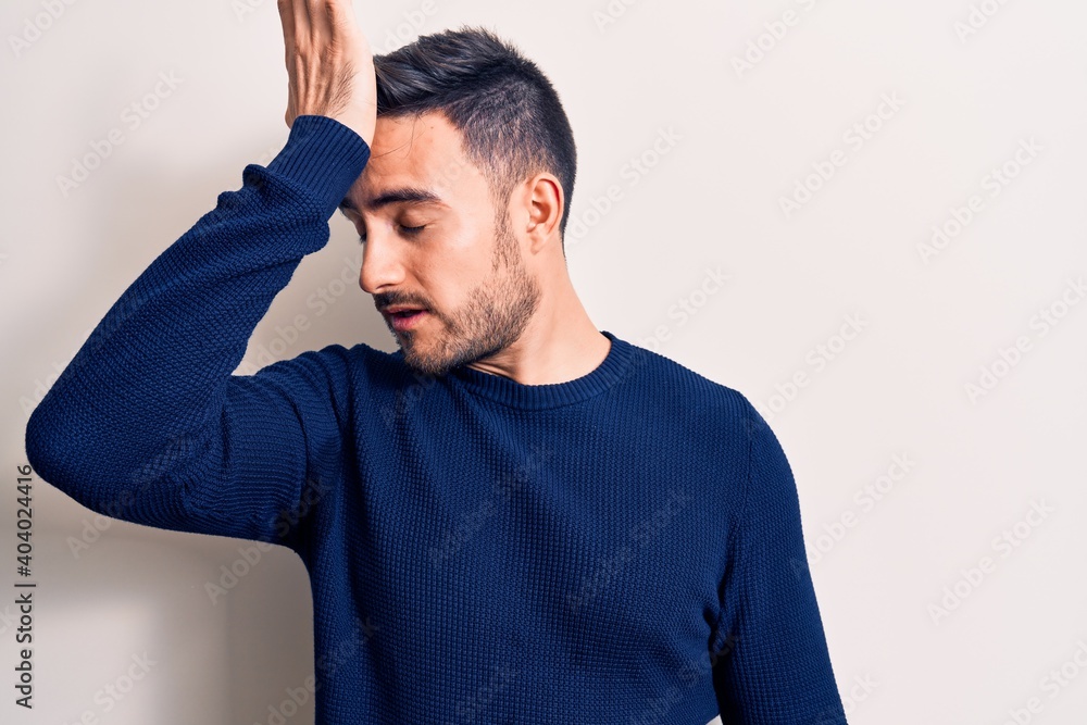 Young handsome man with beard wearing casual sweater standing over white background surprised with hand on head for mistake, remember error. Forgot, bad memory concept. Young handsome man with beard wearing casual sweater standing over white background surprised with hand on head for mistake, remember error. Forgot, bad memory concept.