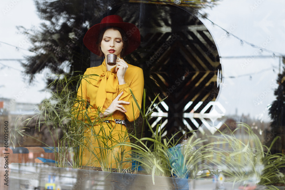 girl in a cafe with a cup of coffee and a hat. beautiful girl with a cup of coffee near the window in a cafe, waiting for a meeting, breakfast girl in a cafe with a cup of coffee and a hat. beautiful girl with a cup of coffee near the window in a cafe, waiting for a meeting, breakfast