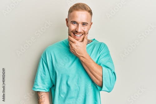 Young caucasian man wearing casual clothes looking confident at the camera smiling with crossed arms and hand raised on chin. thinking positive. © Krakenimages.com