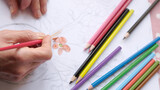 Selective focused woman painting a flower with brush.woman paints the flower orange.Colorful crayons,flower drawing and female hands.Leisure activity.
