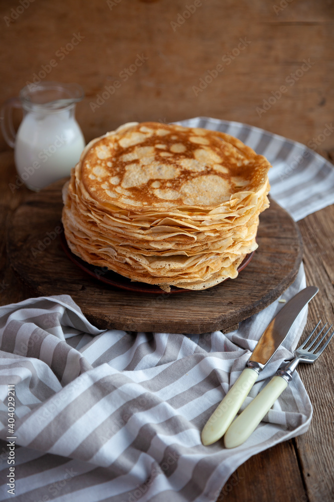 Thin fried pancakes on a plate. Traditional food for Shrovetide. Pancake with sour cream on a wooden table. Thin fried pancakes on a plate. Traditional food for Shrovetide. Pancake with sour cream on a wooden table.