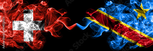 Switzerland  Swiss vs Democratic Republic of the Congo smoky mystic flags placed side by side. Thick colored silky abstract smoke flags.