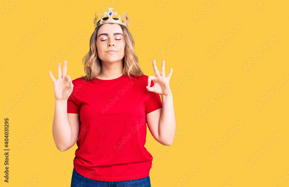 Young caucasian woman wearing princess crown relax and smiling with eyes closed doing meditation gesture with fingers. yoga concept. Young caucasian woman wearing princess crown relax and smiling with eyes closed doing meditation gesture with fingers. yoga concept.