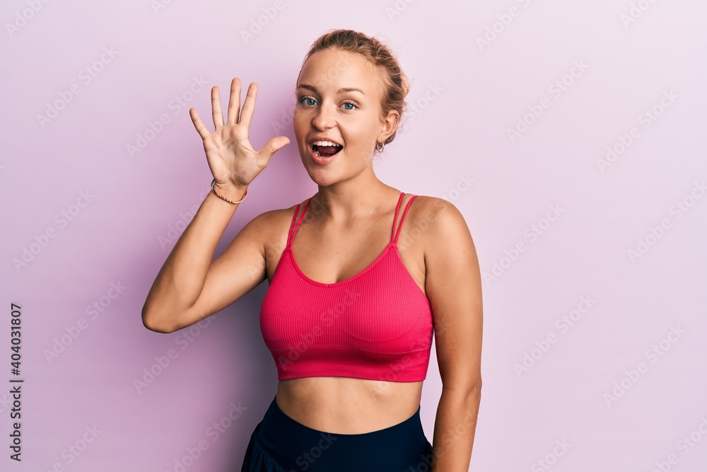 Beautiful caucasian woman wearing sportswear showing and pointing up with fingers number five while smiling confident and happy. Beautiful caucasian woman wearing sportswear showing and pointing up with fingers number five while smiling confident and happy.