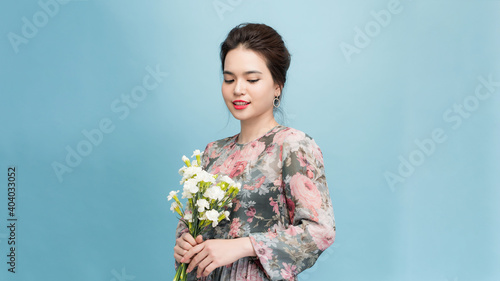 Adorable, beautiful woman holding bouquet of flowers isolated on blue background