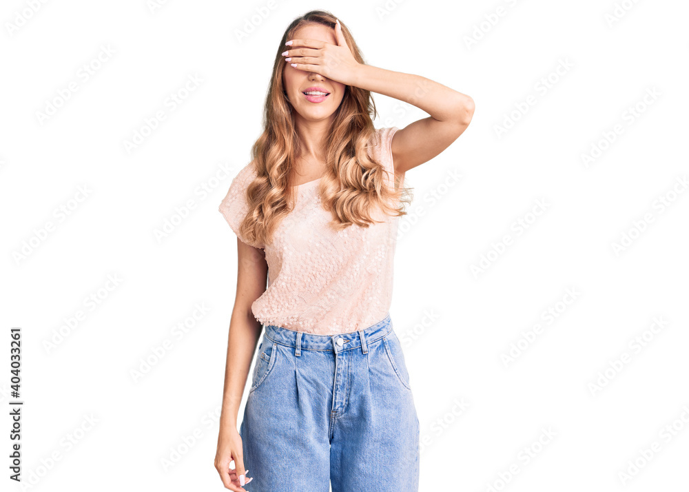 Young beautiful caucasian woman with blond hair wearing casual clothes smiling and laughing with hand on face covering eyes for surprise. blind concept. Young beautiful caucasian woman with blond hair wearing casual clothes smiling and laughing with hand on face covering eyes for surprise. blind concept.