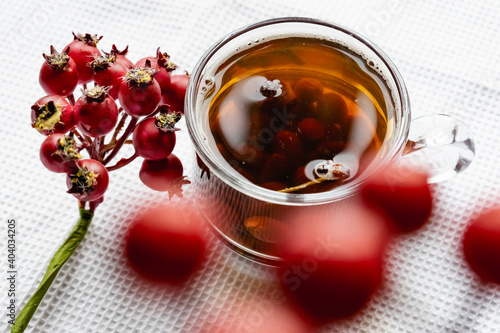 Fruit tea made from berries and rosehip fruits in a transparent glass mug. Hot drink like fresh compote on a white towel