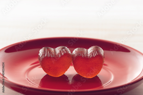 two gummy hearts on a red dish