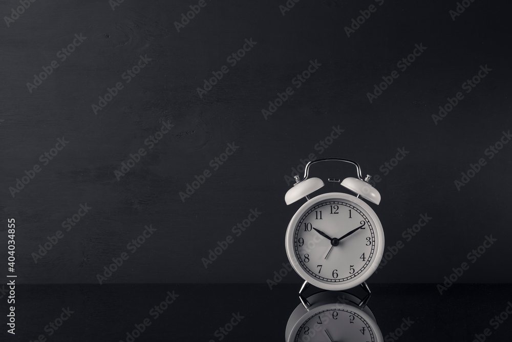 White alarm clock on black glass surface White alarm clock on black glass surface