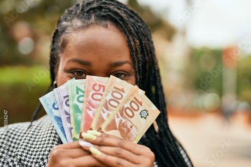 Young african american businesswoman smiling happy covering face with canadian dollars at the park. photo