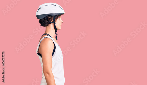 Beautiful young woman with short hair wearing bike helmet looking to side, relax profile pose with natural face with confident smile.