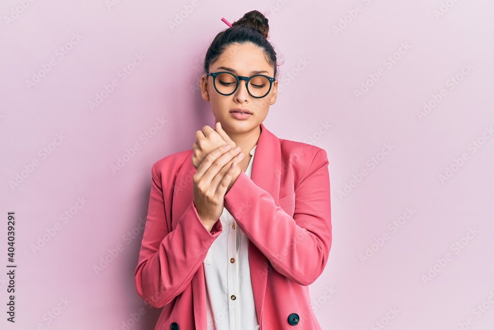 Beautiful middle eastern woman wearing business jacket and glasses suffering pain on hands and fingers, arthritis inflammation