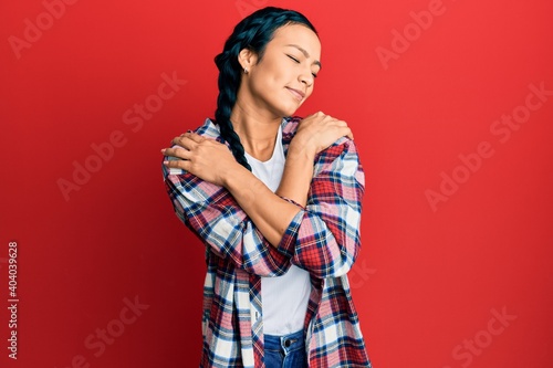 Beautiful hispanic woman wearing casual clothes hugging oneself happy and positive, smiling confident. self love and self care