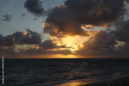 Beautiful sunset on the coast, orange rays of the sun through the clouds on the beach in the evening