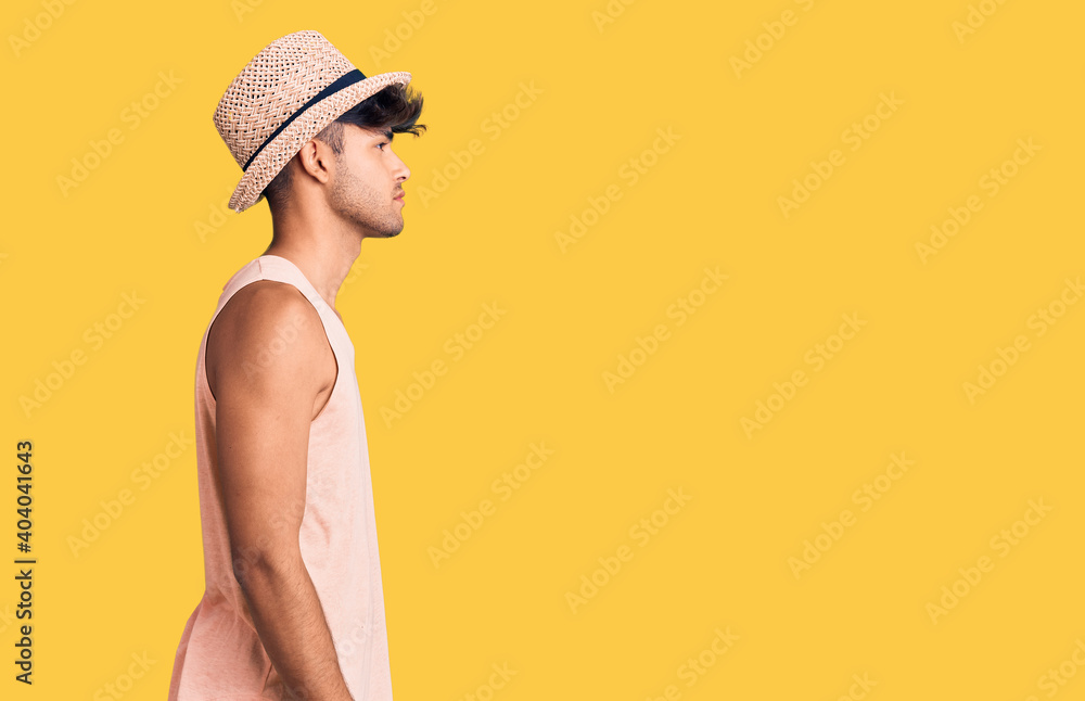Young hispanic man wearing summer hat looking to side, relax profile pose with natural face with confident smile.