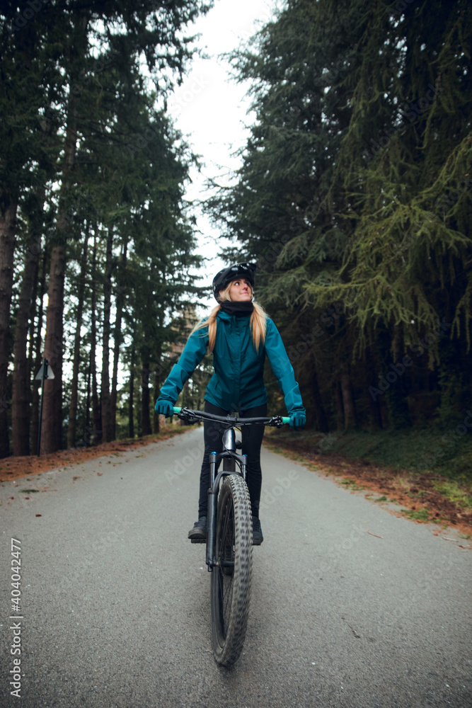 Cyclist girl with mountain bike pedaling on the road in Forest Cyclist girl with mountain bike pedaling on the road in Forest