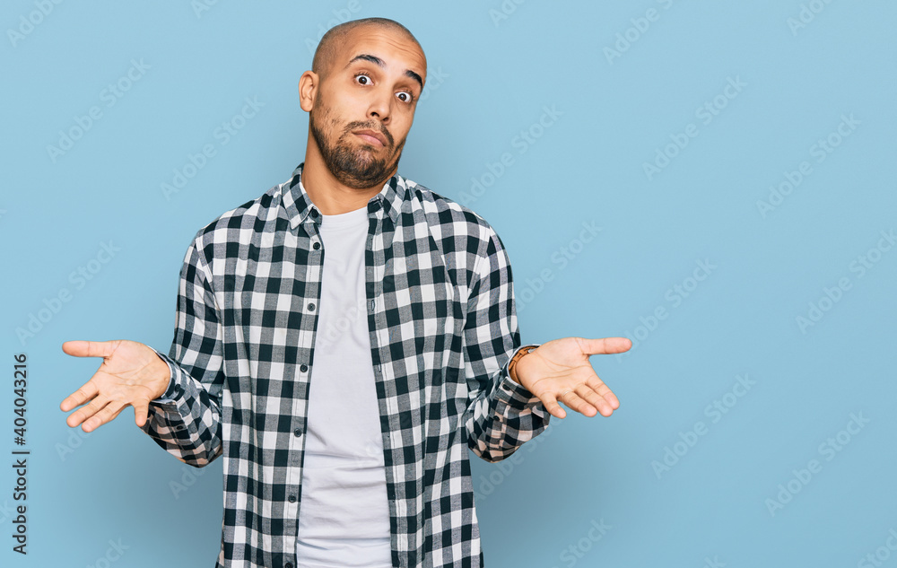Fototapeta premium Hispanic adult man wearing casual clothes clueless and confused expression with arms and hands raised. doubt concept.