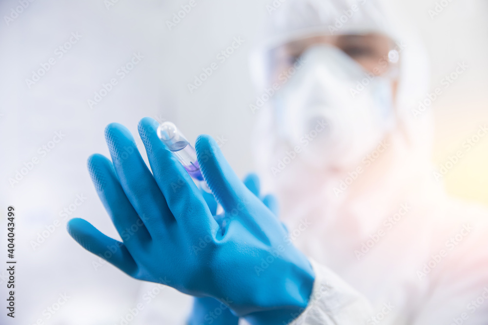 Doctor nurse in protective suit and blue gloves is filling syringe with vaccine against virus or flu. Human vaccination world concept Doctor nurse in protective suit and blue gloves is filling syringe with vaccine against virus or flu. Human vaccination world concept