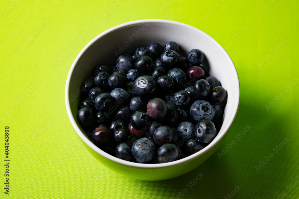 Fresh blueberries in a bowl with green background Fresh blueberries in a bowl with green background