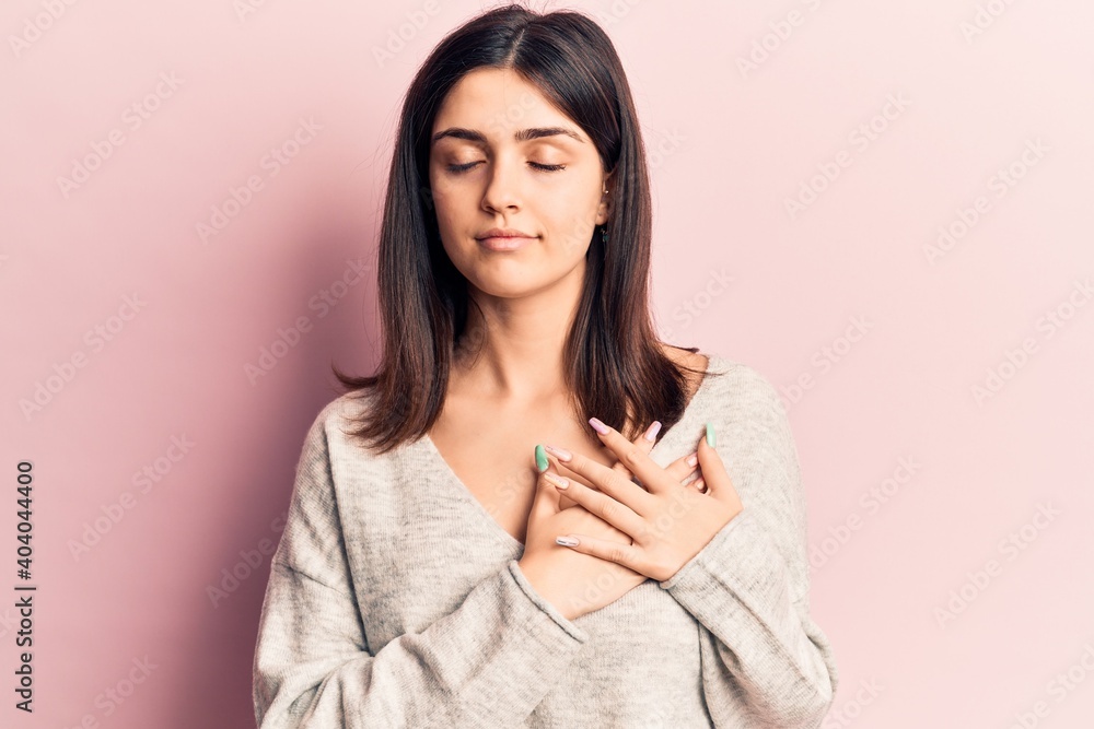 Young beautiful girl wearing casual sweater smiling with hands on chest, eyes closed with grateful gesture on face. health concept. Young beautiful girl wearing casual sweater smiling with hands on chest, eyes closed with grateful gesture on face. health concept.