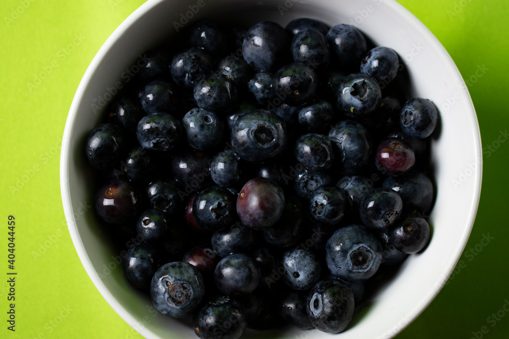 Fresh blueberries in a bowl with green background Fresh blueberries in a bowl with green background