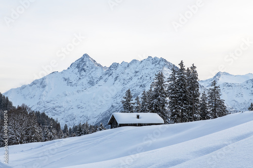winter mountain scene with a alpine hut and a mountain peak