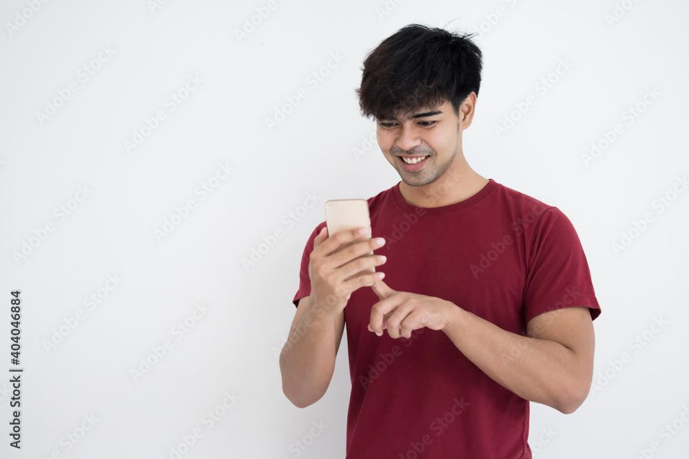 Asian man in red t-shirt using smartphone on gray background Asian man in red t-shirt using smartphone on gray background