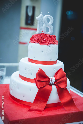 Vertical selective focus shot of a three-layered birthday cake with number 18 photo