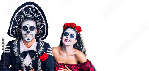 Young couple wearing mexican day of the dead costume over background smiling and laughing hard out loud because funny crazy joke with hands on body.