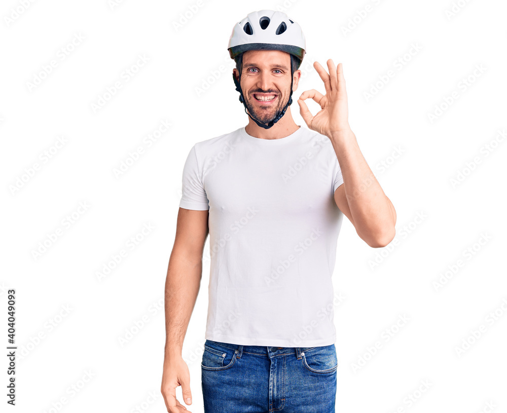 Young handsome man wearing bike helmet smiling positive doing ok sign with hand and fingers. successful expression. Young handsome man wearing bike helmet smiling positive doing ok sign with hand and fingers. successful expression.