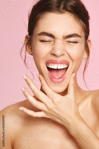 Beauty face. Vertical shot of happy girl laughing and smiling with white perfect teeth, posing half-naked with clean glowing skin, clean face with moisturizers and facial toners, pink background